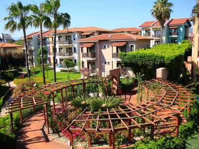 Světelný hotelový komplex s palmami, zalesněnými pergolami a dobře udržovanými cestami.