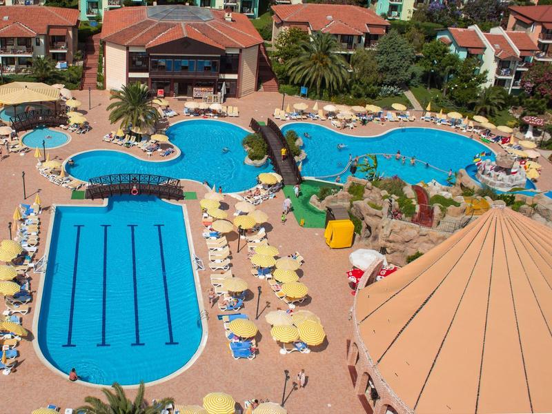 Prostorná venkovní plocha se dvěma bazény, lehátky a slunečníky v hotelovém rezortu.