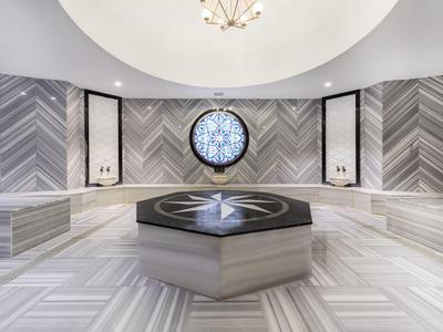 Modern Turkish hammam with geometric marble tiles and round window