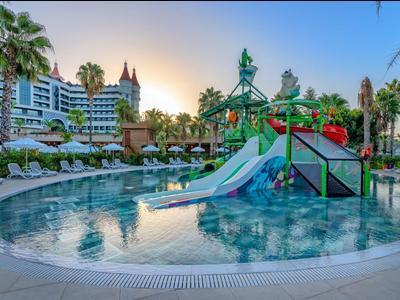 Water park with slides and palm trees at a hotel resort at sunset.