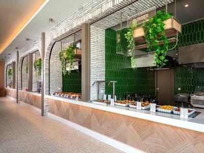 Modern buffet area with green wall tiles and plants in a hotel.