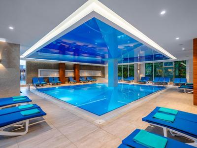 Modern indoor pool area with blue loungers and large windows