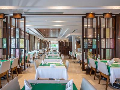 Bright, modern dining room with green placemats and wood-paneled walls in a hotel.