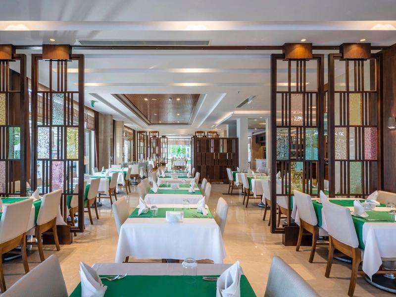 Bright, modern dining room with green placemats and wood-paneled walls in a hotel.
