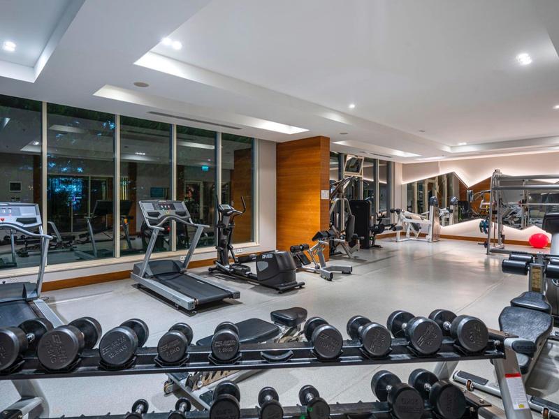 Modern gym with dumbbells, treadmills, and strength training equipment in a hotel.