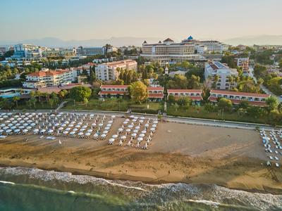 Widok na plażę z leżakami i hotelami w tle pod czystym niebem.