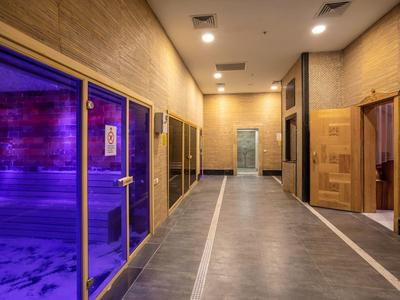 Nowoczesna strefa wellness z sauną i drewnianym wnętrzem o ciepłym oświetleniu.