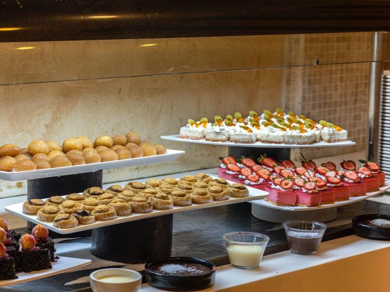 Lada z różnymi małymi ciastkami, tartami i deserami w części bufetowej.