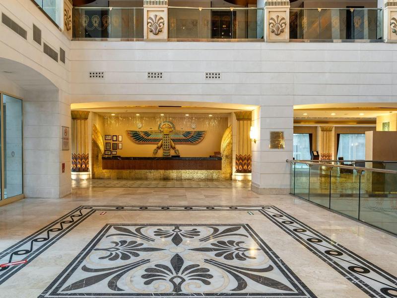 Elegancka lobby hotelowa z kwiatowymi mozaikami, marmurowymi podłogami i luksusowym oświetleniem.