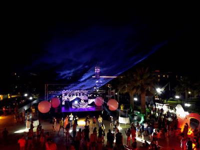 Persone che si godono un evento notturno all'aperto con un palco e luci.