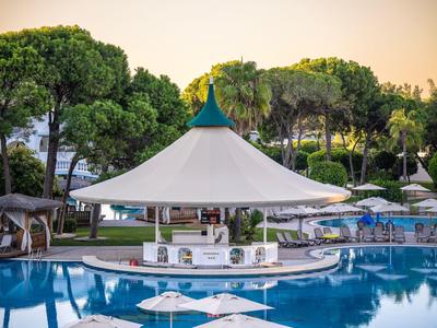 Piscina esterna con ombrelloni e padiglione davanti ad alberi al tramonto