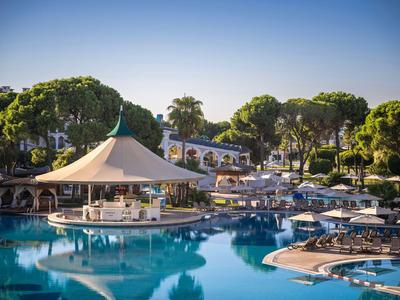 Luksusowy basen hotelowy z parasolami, leżakami i drzewami wokół pod czystym niebem.