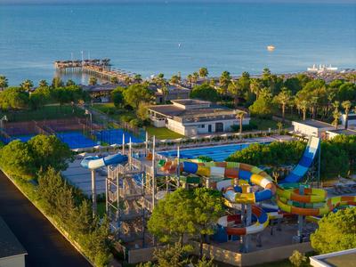 Widok na park wodny z kolorowymi zjeżdżalniami obok kortów tenisowych nad morzem.