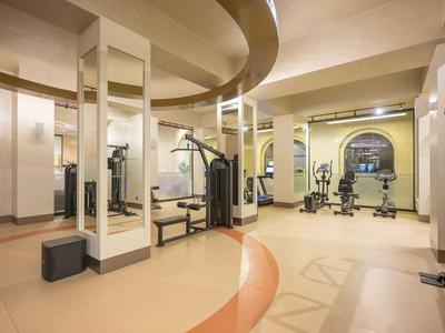 Nowoczesna siłownia z różnym sprzętem do ćwiczeń oraz ścianami z lustrem.
