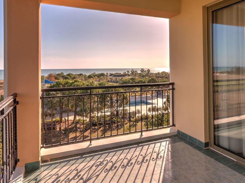 Balcón con vista a árboles y mar al atardecer