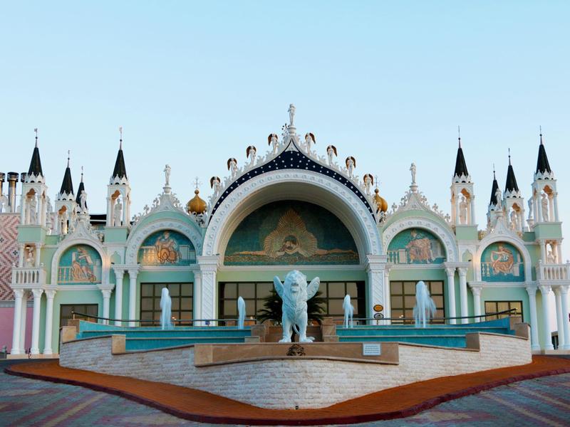 Un edificio blanco ornamentado con torres y una fuente delante bajo un cielo despejado.