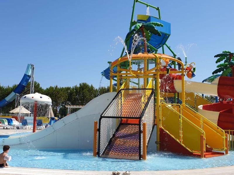 Parque acuático con toboganes de colores y piscina bajo cielo azul claro.