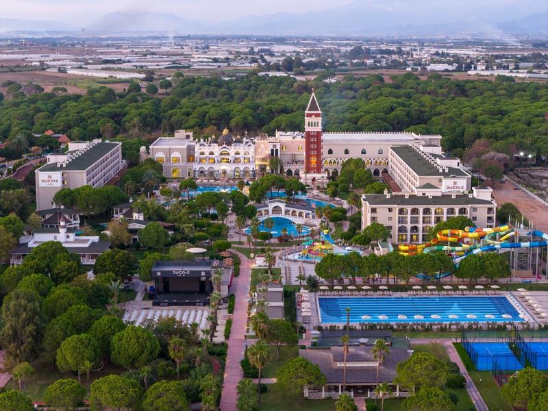 Vista aérea de un resort con piscinas, toboganes acuáticos y amplios jardines en un entorno urbano.