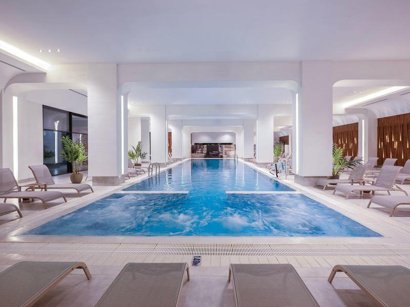 Piscina interior moderna en un hotel de lujo con tumbonas y ambiente relajante.