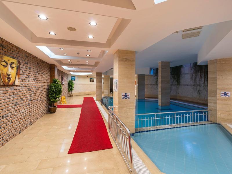 Interior de un hotel con piscina, alfombra roja y arte en la pared de ladrillo.