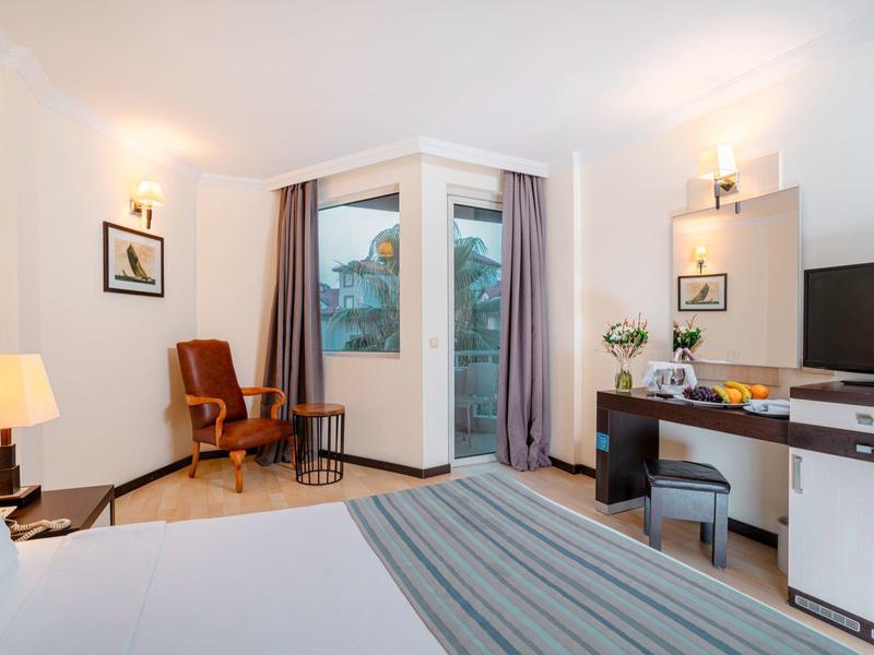 Habitación de hotel acogedora con sillón, escritorio, TV y balcón con vista.