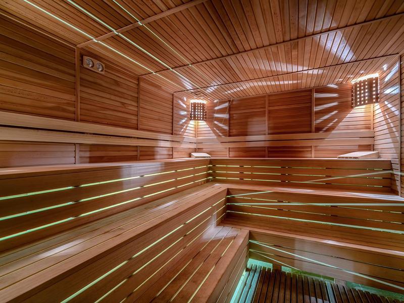 Sauna moderna y luminosa con bancos de madera y luz cálida en tonos de madera.