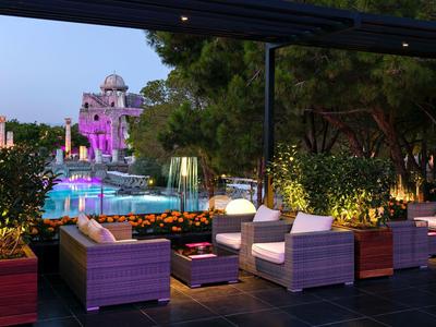 Mobilier de salon éclairé sur la terrasse avec vue sur piscine illuminée et tour au crépuscule