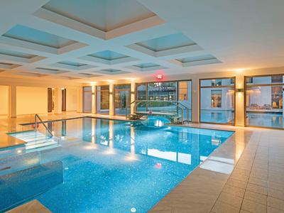 Heller Innenpool mit blauem Wasser, großen Fenstern und moderner Deckengestaltung.