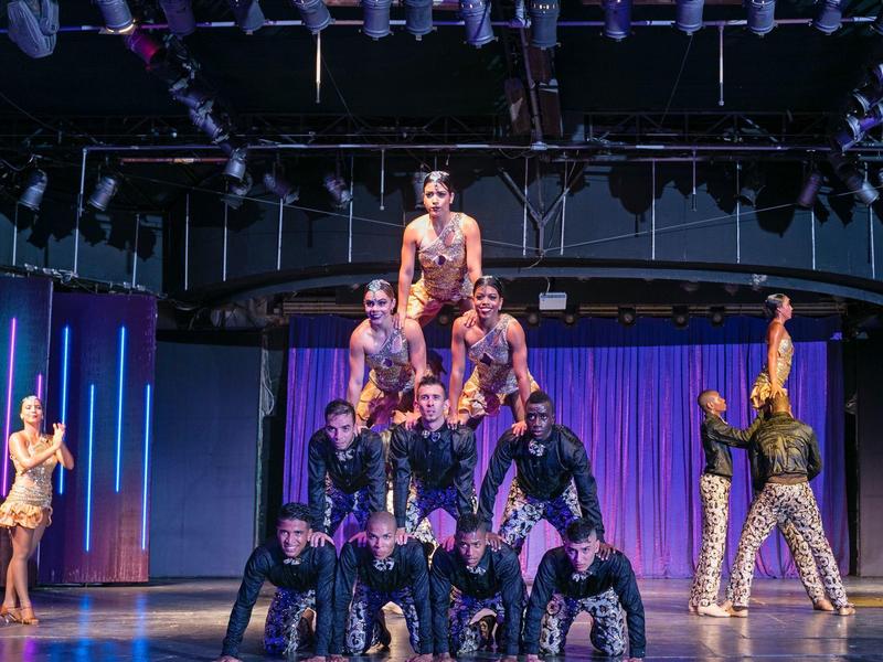 Des personnes forment une pyramide humaine sur une scène avec un éclairage coloré.