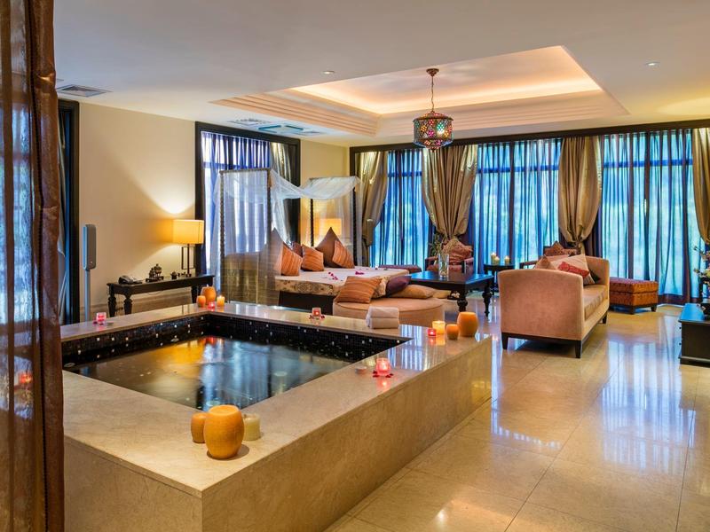 Espace lounge d'hôtel élégant avec grand bassin d'eau, canapés et éclairage d'ambiance.