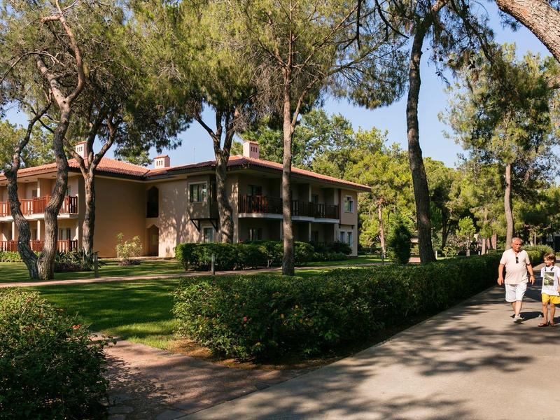 Deux personnes marchent sur un chemin entouré d'arbres à côté d'un bâtiment de deux étages.