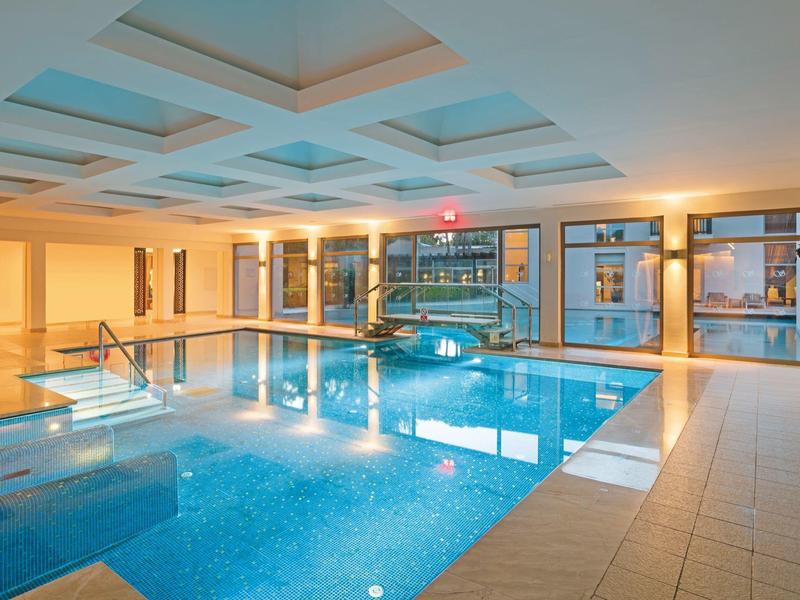Piscine intérieure lumineuse et moderne avec grandes fenêtres et jacuzzi dans un hôtel.
