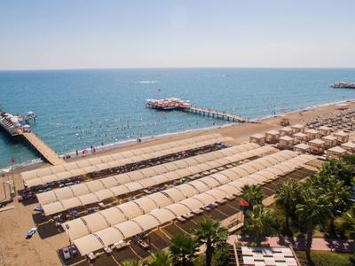 Strand mit Liegestühlen und Sonnenschirmen neben zwei Bootsanlegern am Meer