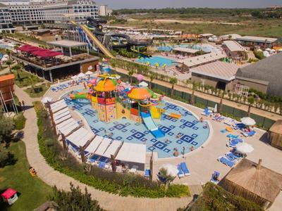 Rekreační areál s vodním parkem, bazény a skluzavkami vedle řeky v slunné krajině.