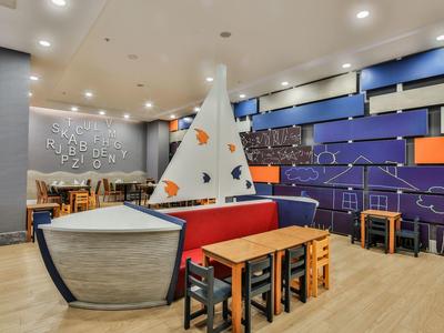 Moderní hotelová lobby s barevným sezením a námořnickým plachtovým designem na zdi.