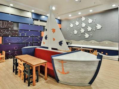 Dětský koutek s lodním tématem a barevnými stoly v hotelovém interiéru.