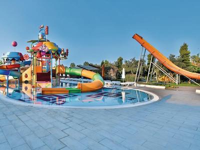 Barevný vodní park s několika skluzavkami a bazénky za slunečného počasí.