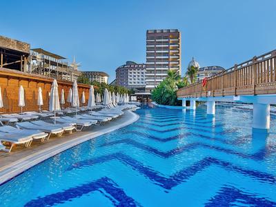 Duży basen na zewnątrz z leżakami i budynkiem hotelu w tle pod czystym niebem.