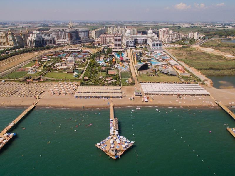 Letecký pohled na širokou pláž s moly, budovami a městem v pozadí.