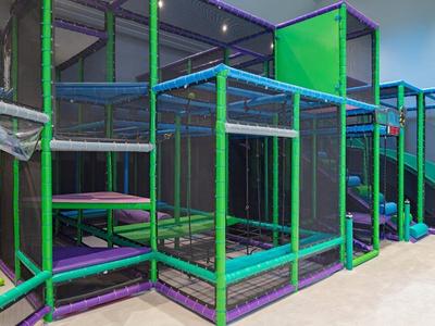 Area giochi interna con strutture per arrampicarsi e scivolo dai colori vivaci.