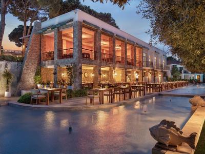 Ristorante moderno vicino all'acqua con illuminazione calda e posti a sedere all'aperto al crepuscolo.