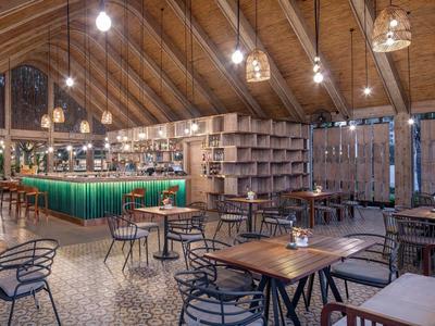 Ampio bar con tavoli in legno, sgabelli e un bancone verde illuminato in un edificio in legno.