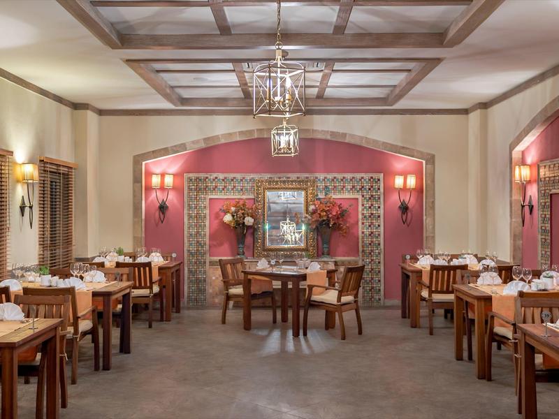 Ristorante elegante con soffitto a pannelli di legno, lampadario e tavoli apparecchiati.
