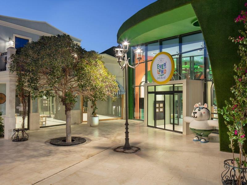 Cortile di un hotel con piante, panchine e ingresso moderno al crepuscolo.