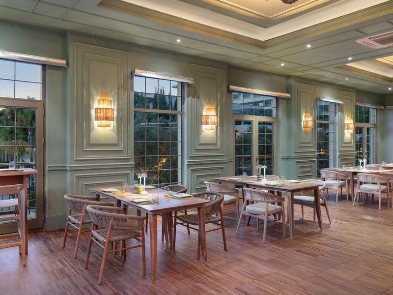 Area ristorante dell'hotel luminosa con tavoli in legno e grandi finestre che si affacciano sulla natura.