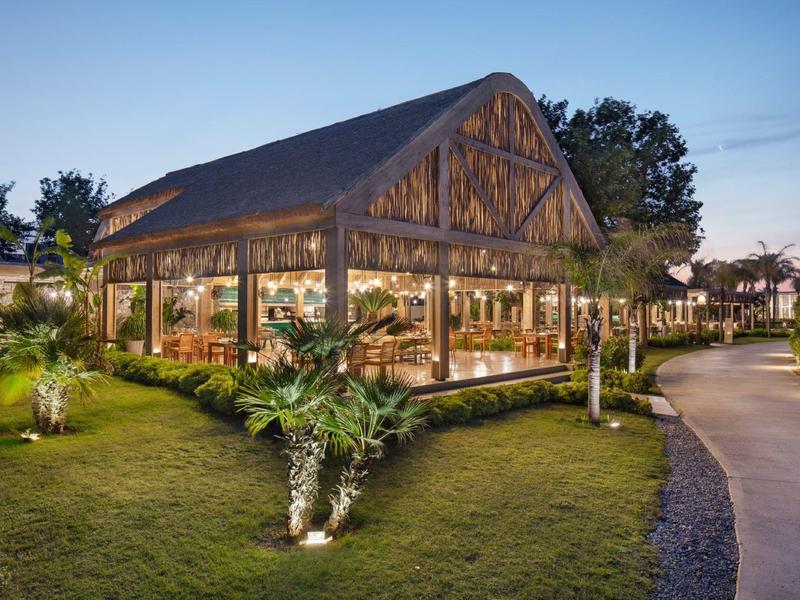 Edificio in legno aperto e illuminato in un ambiente verde al crepuscolo.