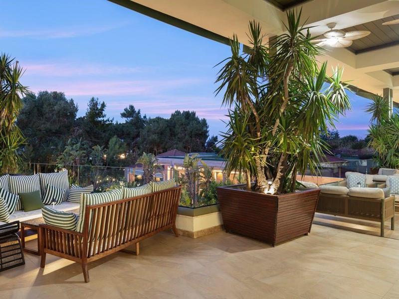 Moderna terrazza dell'hotel aperta con aree salotto comode e piante, vista sul cielo serale.