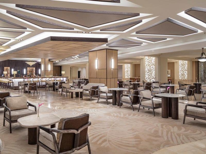 Ampia area lounge di un hotel moderno con sedie comode e lampade da soffitto eleganti.