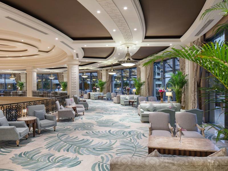 Lussuosa hall d'hotel con mobili moderni, grandi finestre e piante tropicali