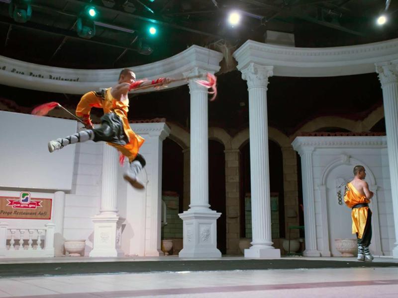 Taneční představení s umělcem skákajícím před bílými sloupy.